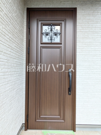 玄関　【日野市落川】
木のぬくもりがあたたかい印象の玄関ドア。
飾りをあしらった明り窓から室内にやさしい明りが入ります。